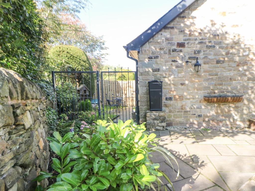 a stone building with a gate and a garden at Causeway Hideaway in Sheffield