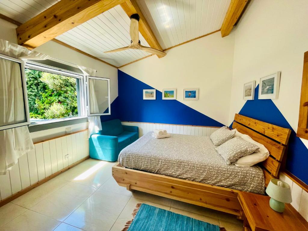 a bedroom with a bed and a blue accent wall at Sea Roots "Garden Zone " in Mosteiros