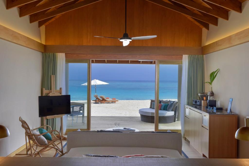 a living room with a view of the beach at Emerald Faarufushi Resort & Spa - Deluxe All Inclusive in Raa Atoll