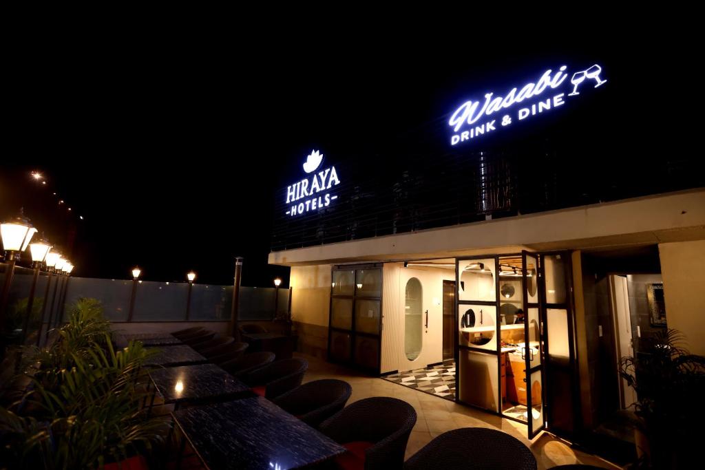 Mohali的住宿－Hiraya Hotels，屋顶上设有椅子和 ⁇ 虹灯标志的餐厅