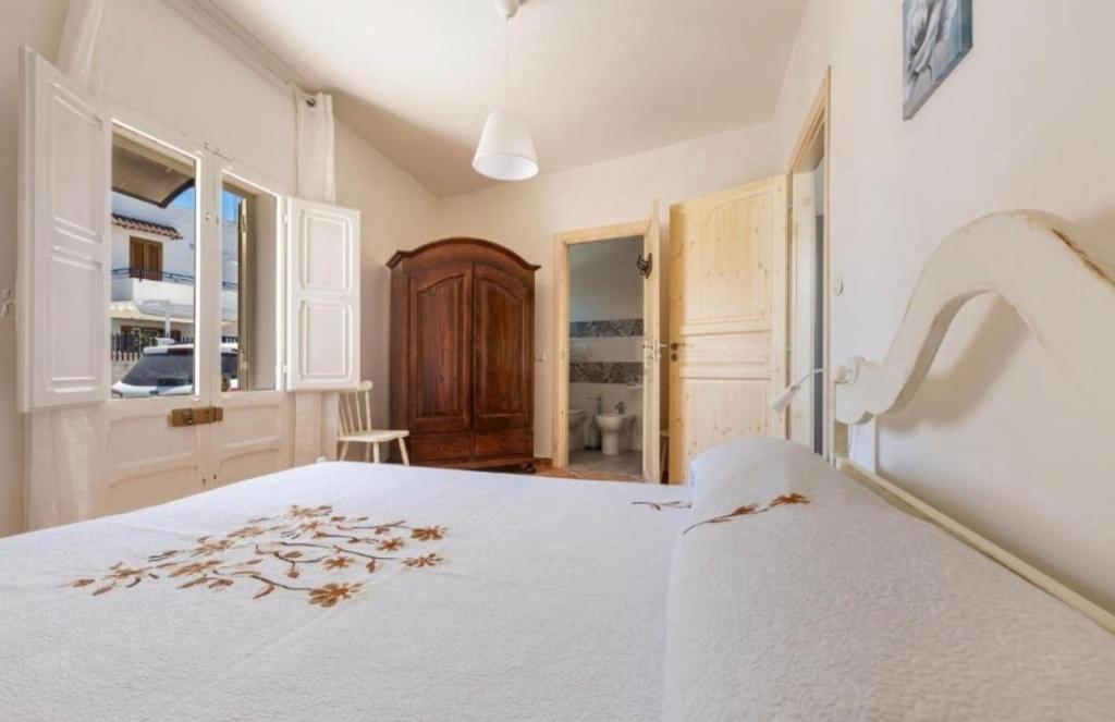 a bedroom with a white bed and a wooden cabinet at La Casetta Al Mar in Porto Cesareo