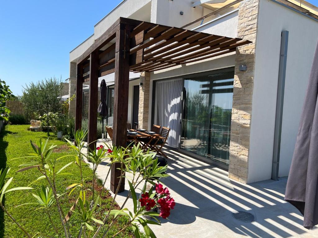 a patio of a house with a wooden pergola at Villa Rosa dei Venti - Peroj - Amazing sea view in Peroj