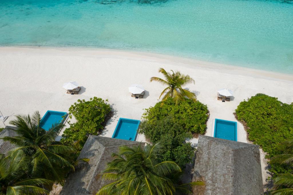 an aerial view of a beach with chairs and umbrellas at Emerald Faarufushi Resort & Spa - Deluxe All Inclusive in Raa Atoll