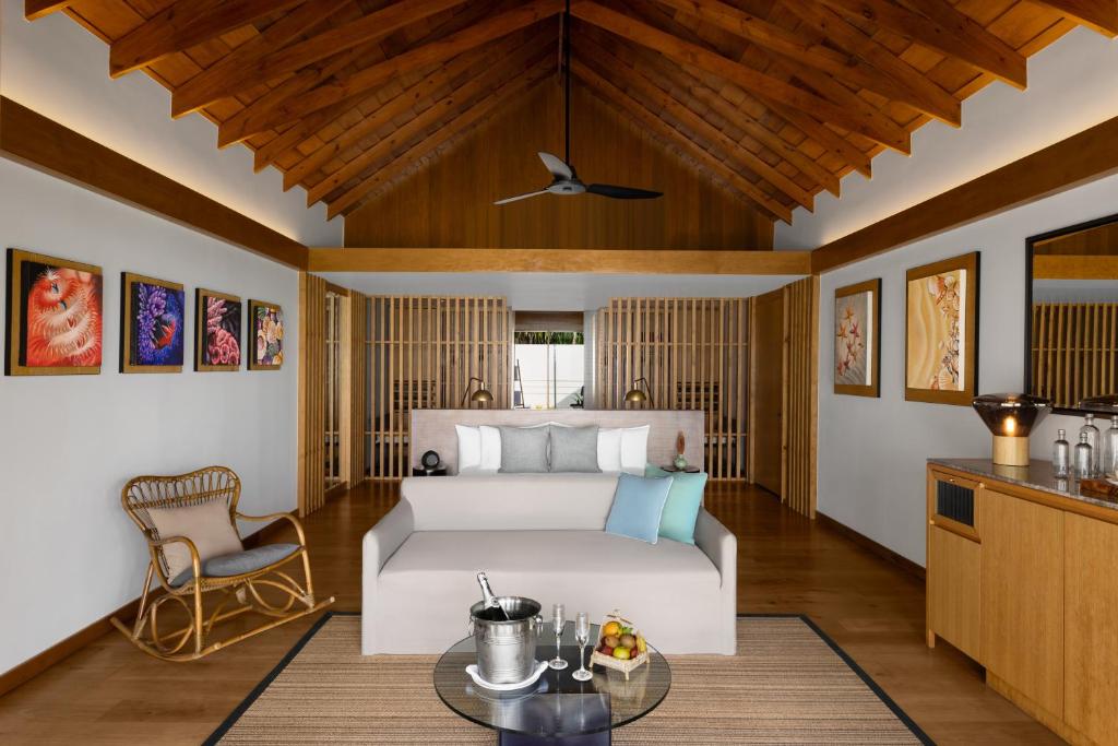 a bedroom with a bed and a table at Emerald Faarufushi Resort & Spa - Deluxe All Inclusive in Raa Atoll