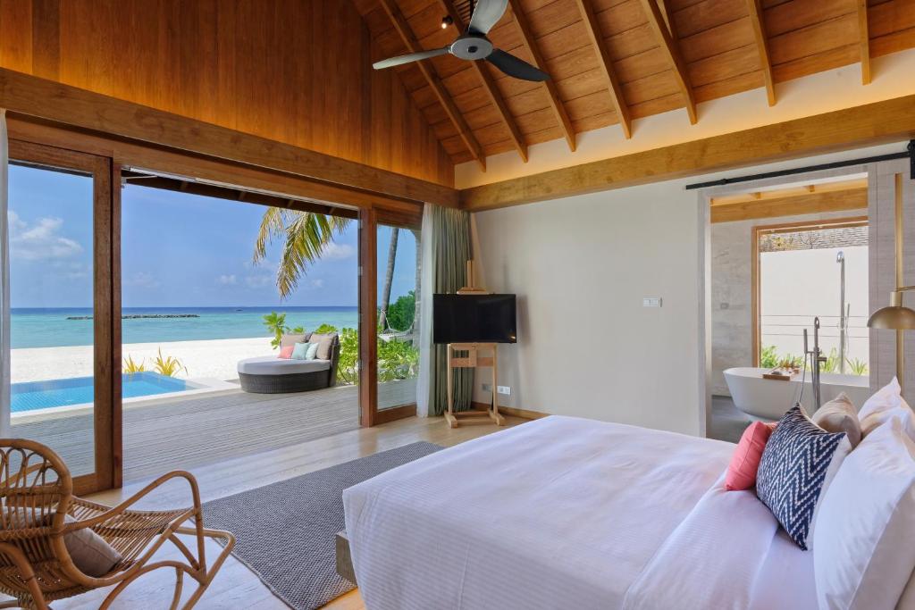 a bedroom with a bed and a view of the ocean at Emerald Faarufushi Resort & Spa - Deluxe All Inclusive in Raa Atoll