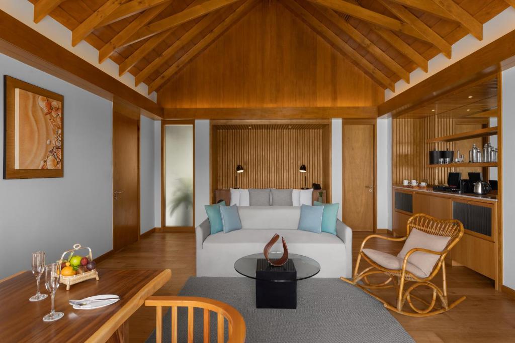 a bedroom with a bed and a table and chairs at Emerald Faarufushi Resort & Spa - Deluxe All Inclusive in Raa Atoll