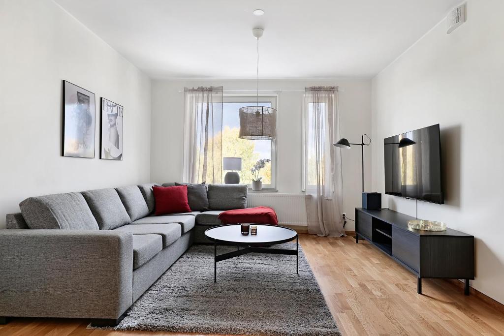 Sala de estar con sofá gris y mesa en Guestly Homes - 1BR Corporate Comfort, en Boden