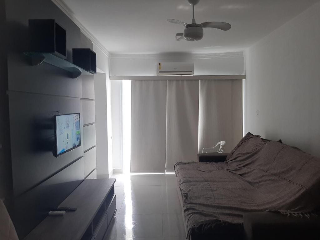 a bedroom with a bed and a television and a window at Apto Guaruja Astúrias in Guarujá