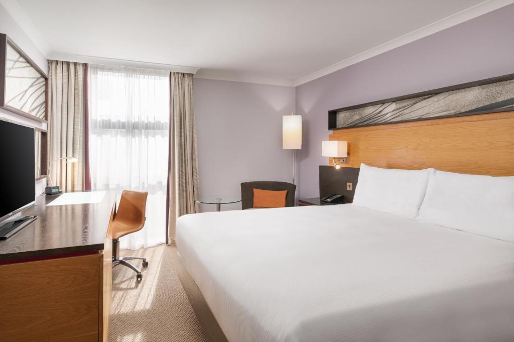 een hotelkamer met een groot bed en een televisie bij Hilton London Kensington Hotel in Londen