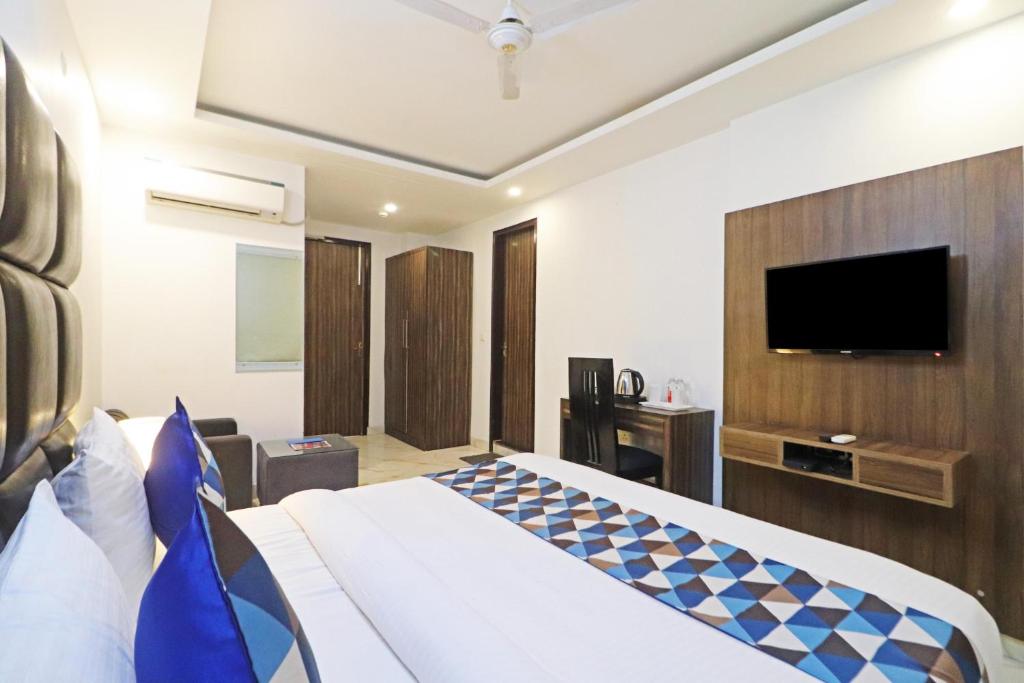 Hotel Mayda Prime Near Delhi Airport في نيودلهي: غرفة فندقية بسرير وتلفزيون بشاشة مسطحة