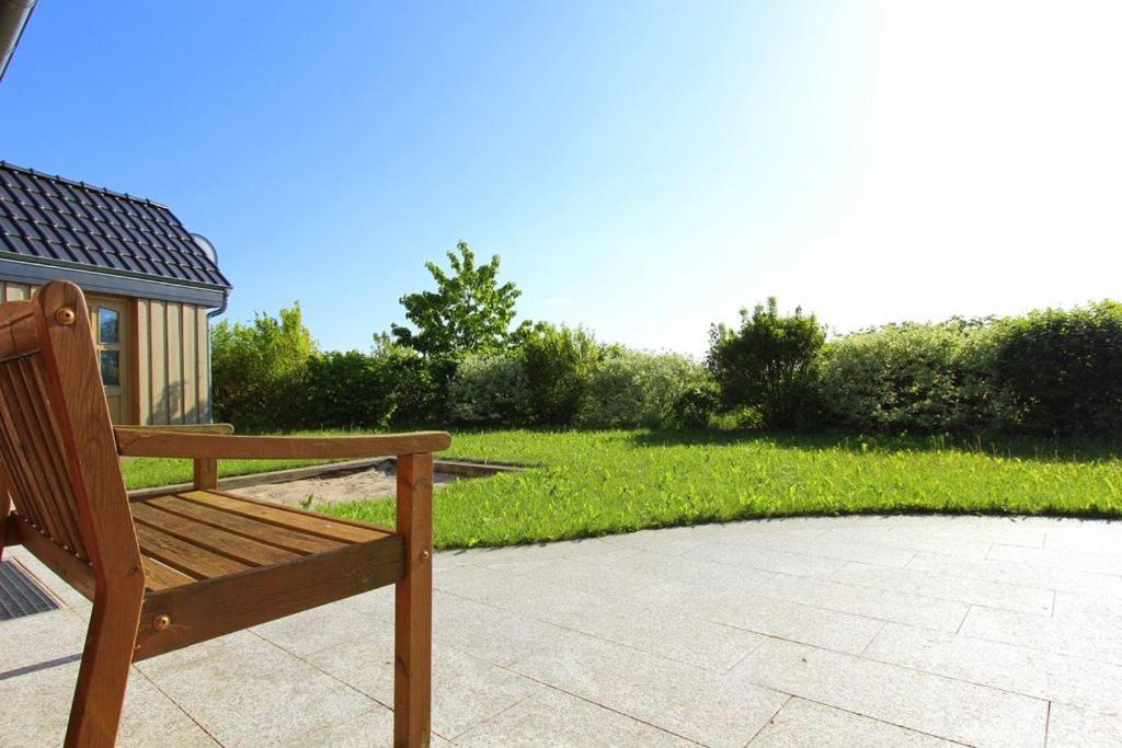 eine Holzbank auf einer Terrasse in einem Hof in der Unterkunft Ferienhaus Strandmuschel in Groß Schwansee