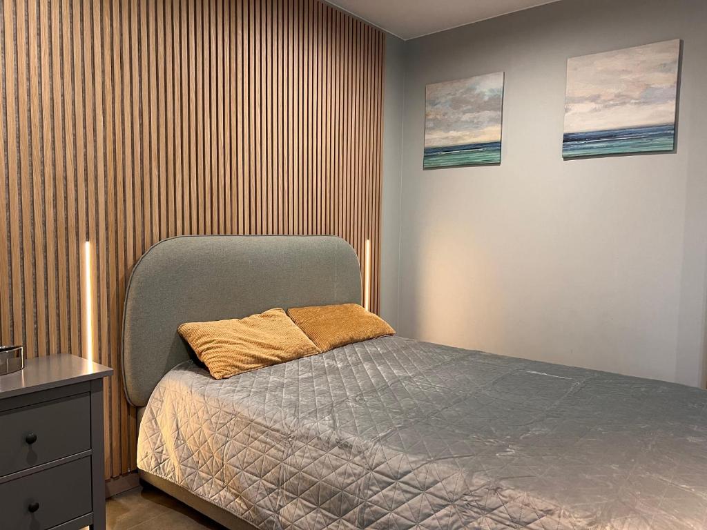 sypialnia z łóżkiem i drewnianą ścianą w obiekcie Apartament Silver Klifowa w Rewalu
