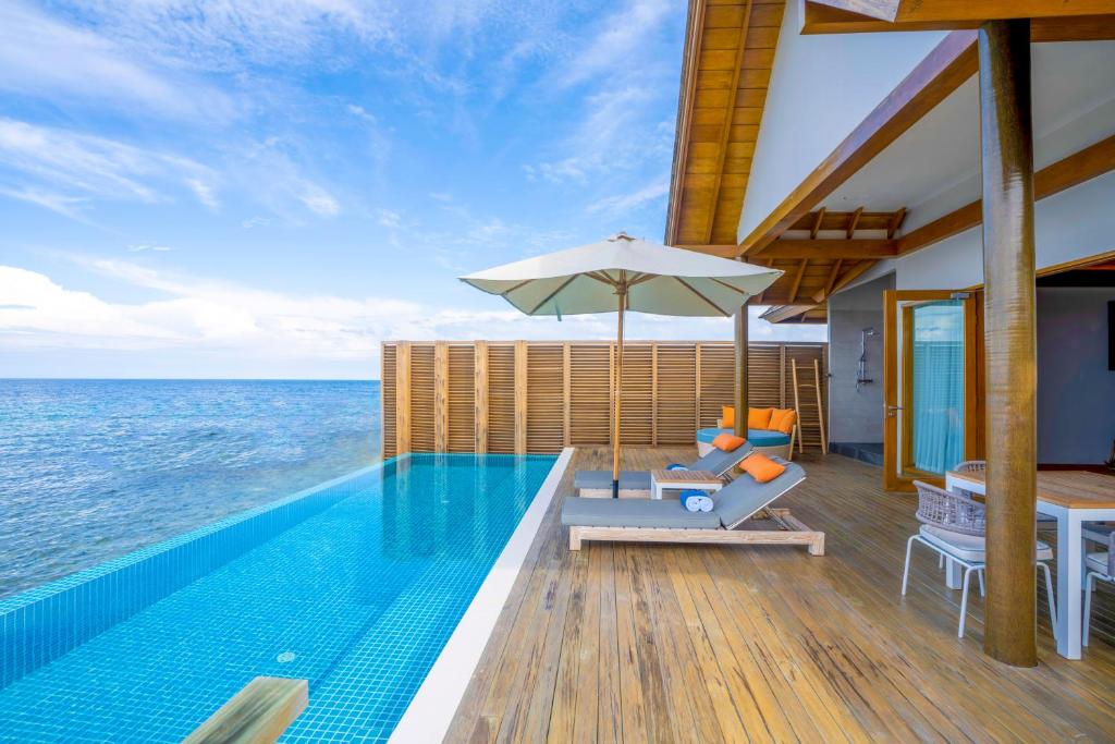 a villa with a swimming pool and an umbrella at Emerald Faarufushi Resort & Spa - Deluxe All Inclusive in Raa Atoll