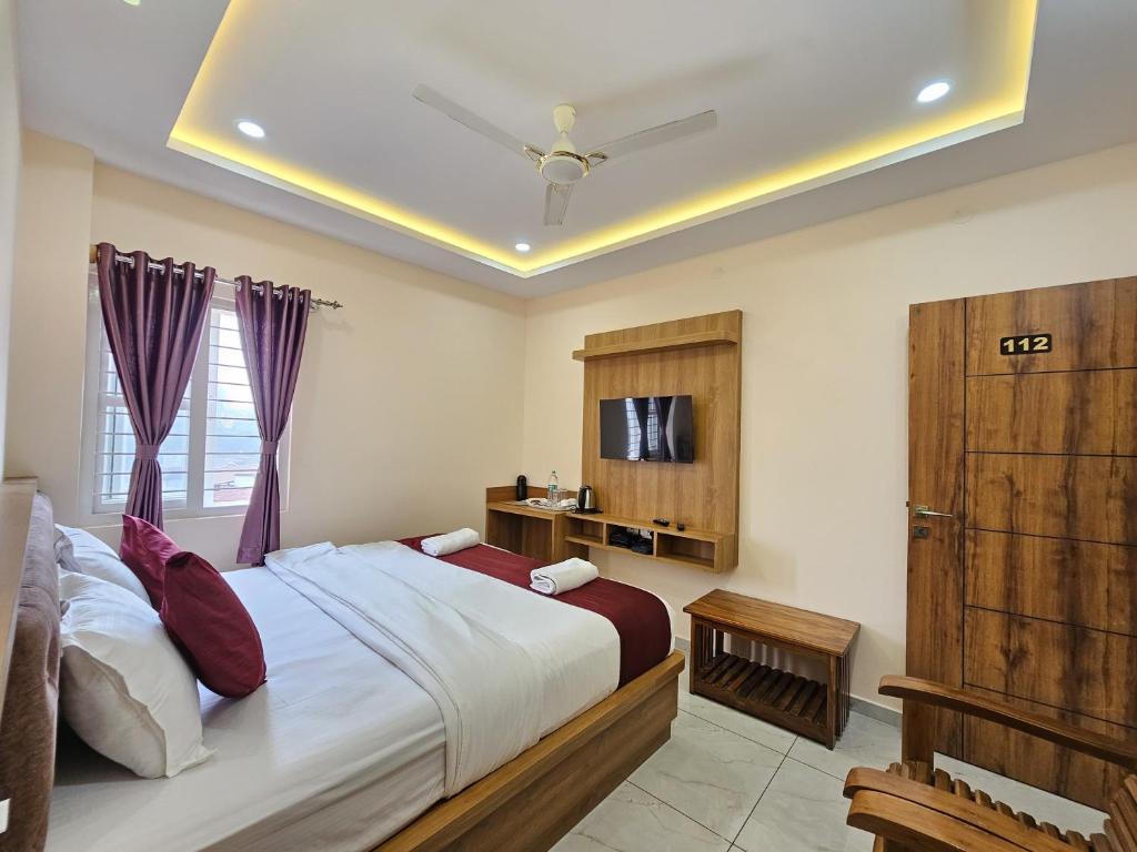 a bedroom with a large bed and a tv at Navarathna Comforts in Madikeri