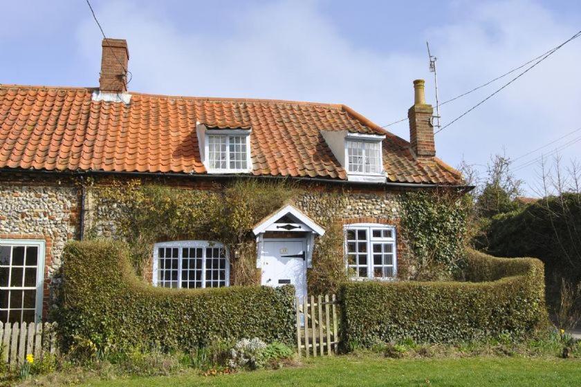 una vieja casa de ladrillo con hiedra creciendo en ella en Brooke Cottage en Little Walsingham