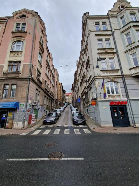 an empty city street with buildings and cars on the street at Una Apartment in Sarajevo