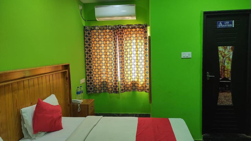 a green bedroom with a bed and a window at SM Residency in Coimbatore
