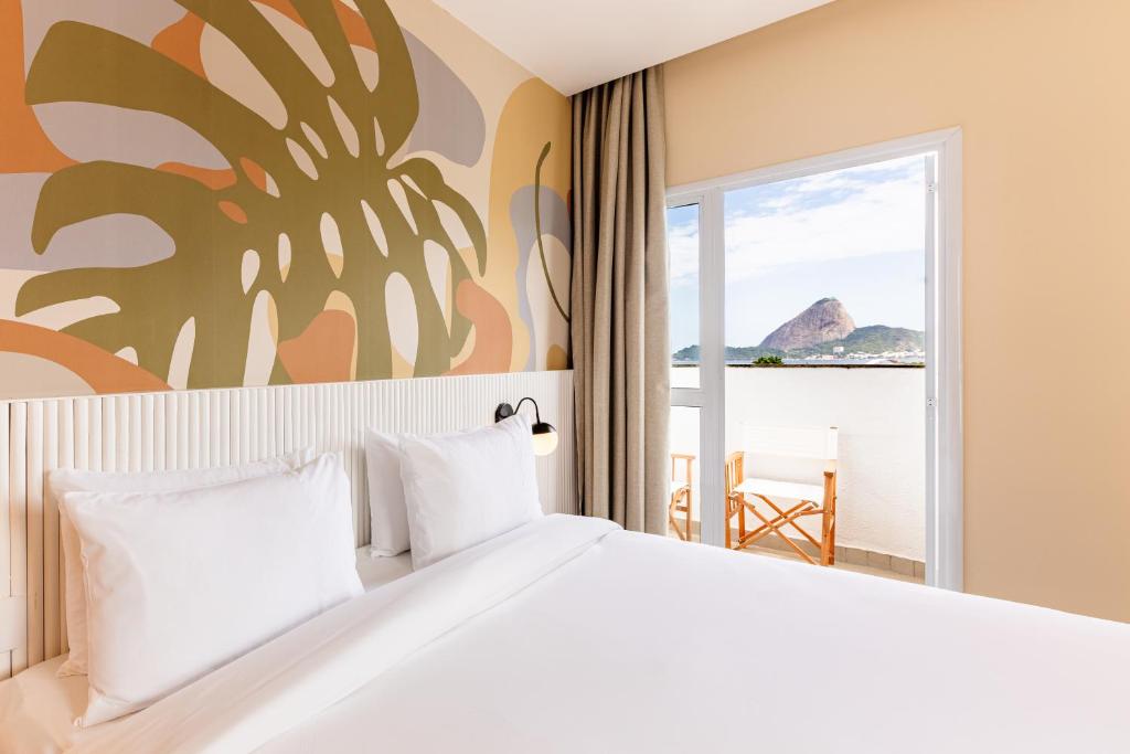 a bedroom with a large bed with a view of the ocean at B&B HOTEL Santos Dumont in Rio de Janeiro