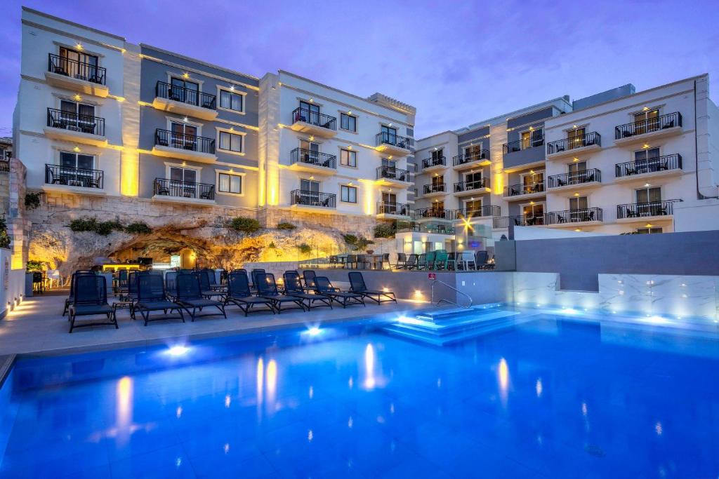 a hotel with a swimming pool in front of a building at Pergola Hotel & Spa in Mellieħa