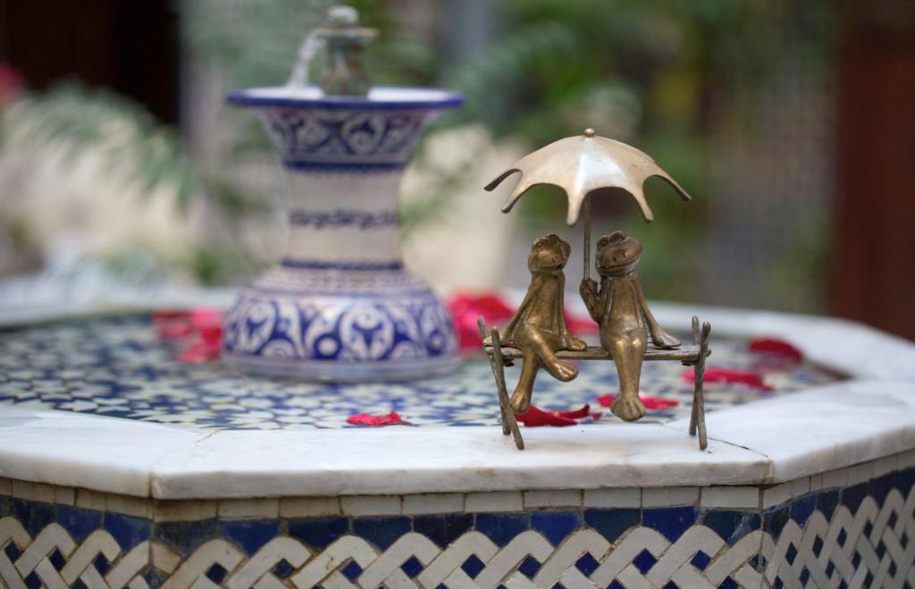 two figurines are holding an umbrella on a table at Riad Fes Kettani in Fez