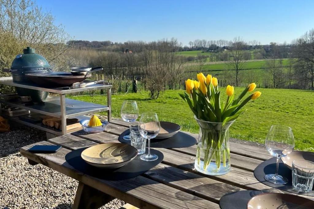 a wooden picnic table with yellow flowers and wine glasses at Welkom in Vloesberg n°54 in Flobecq