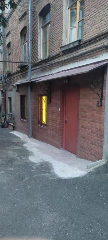 een rood bakstenen gebouw met een deur met een geel gordijn bij Guga gold in Tbilisi City