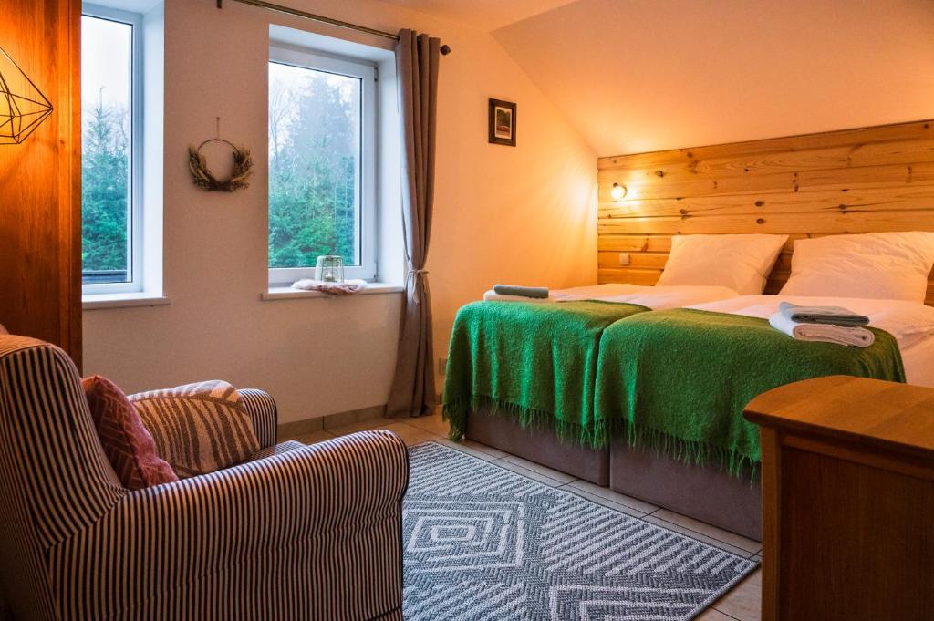a bedroom with a bed with a green blanket and two chairs at Heart of Polen appartements in Piechowice