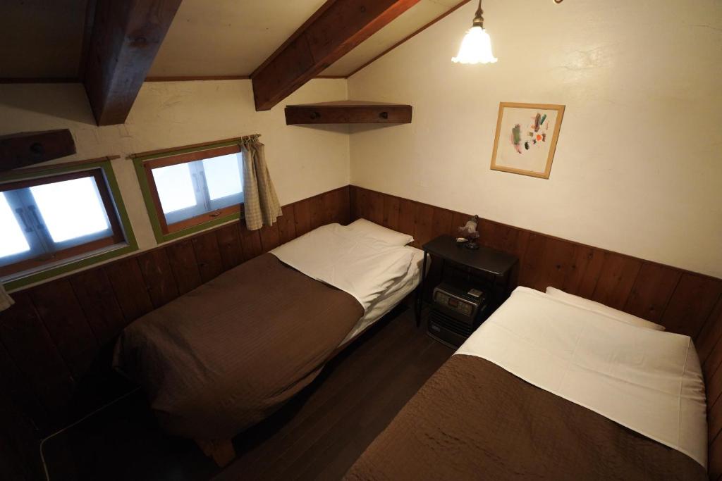 una piccola camera con due letti e una finestra di 白馬シェア 落倉店 Hakuba share-Ochikura a Yotsuya