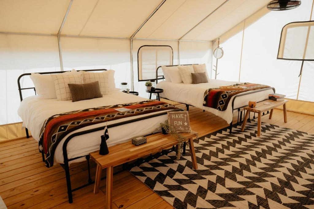 two beds in a room with a table and a rug at Glamping Tents 2 Queens at Lake Guntersville State Park in Guntersville