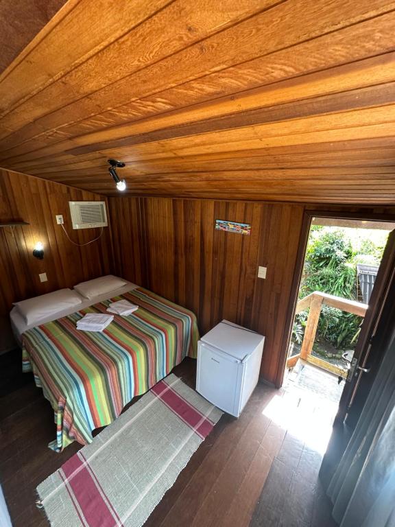a small bedroom with a bed in a wooden room at Pousada Cachoeira in Abraão
