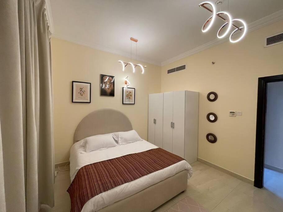 a bedroom with a bed and a chandelier at Lovely 1 Bedroom near to beach in Sharjah