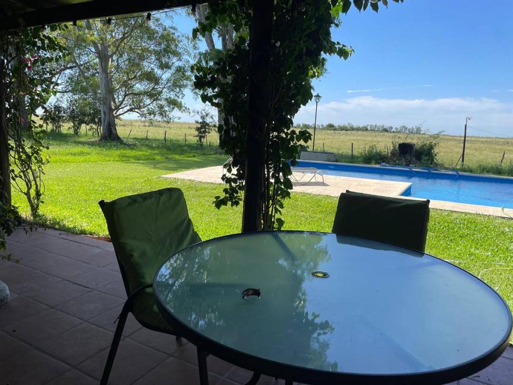 einen Glastisch und Stühle neben einem Pool in der Unterkunft Paz Cerca de Termas Grandes in Gualeguaychú