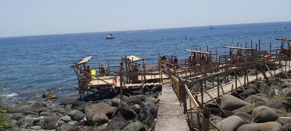 personas en un paseo de madera cerca del agua en Appartamento Gardenhouse, en Aci Trezza