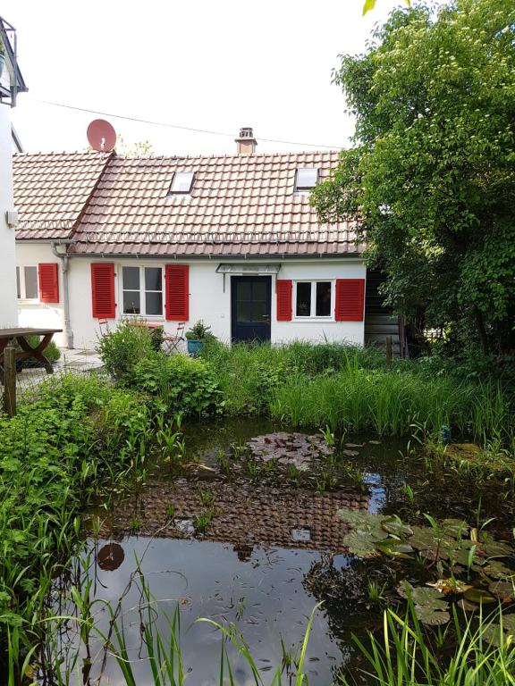 斯圖加特的住宿－Kl. Cottage im Grünen, n. S-Bahn，一座带红色百叶窗和池塘的房子