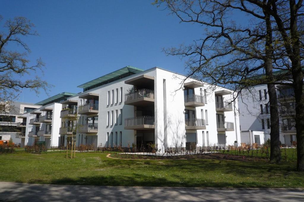 un gran edificio blanco con árboles delante de él en Resid. im Kurpark, Lagune, en Warnemünde