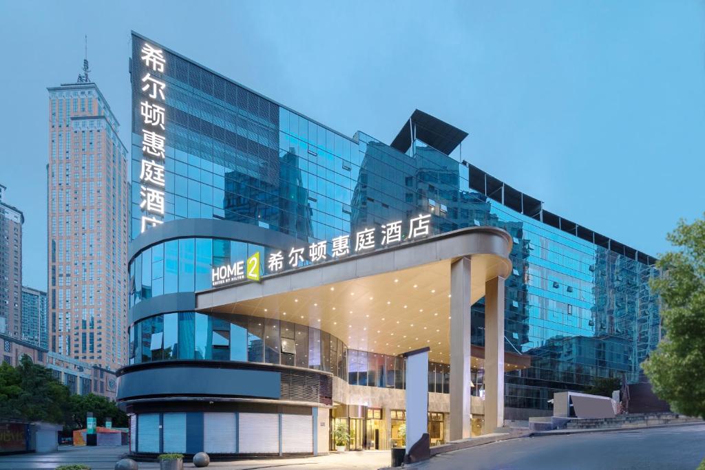 un edificio de cristal con un cartel encima en Home2 Suite by Hilton Chongqing South Bank en Chongqing