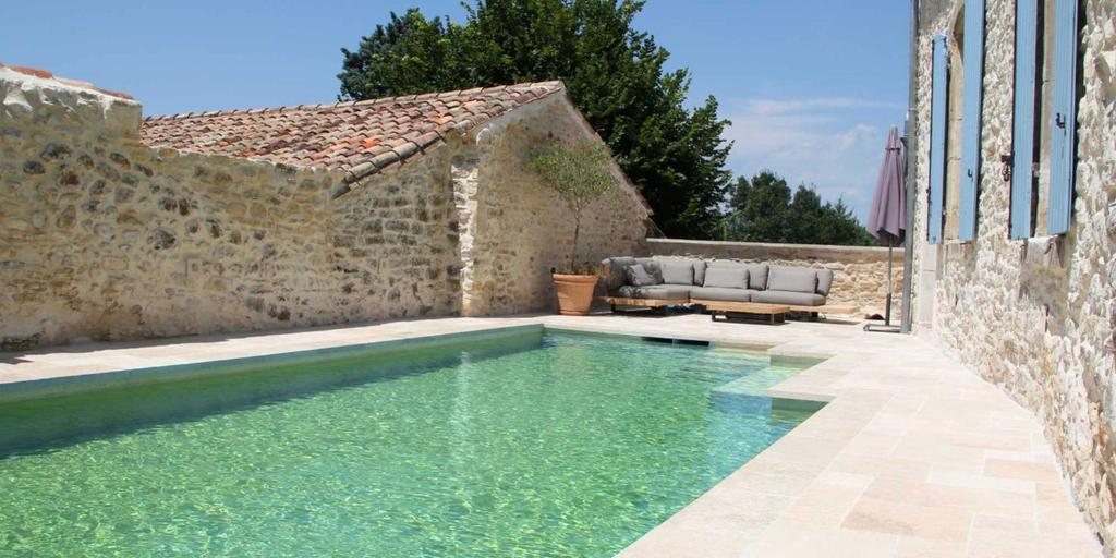 una piscina frente a un edificio de piedra en La Planque des Frères, en Rivières