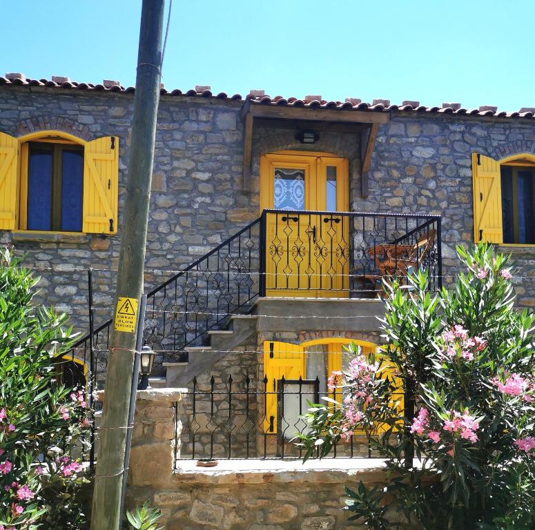 una casa in pietra con porte e scale gialle di Ilios Guest House a Gokceada Town
