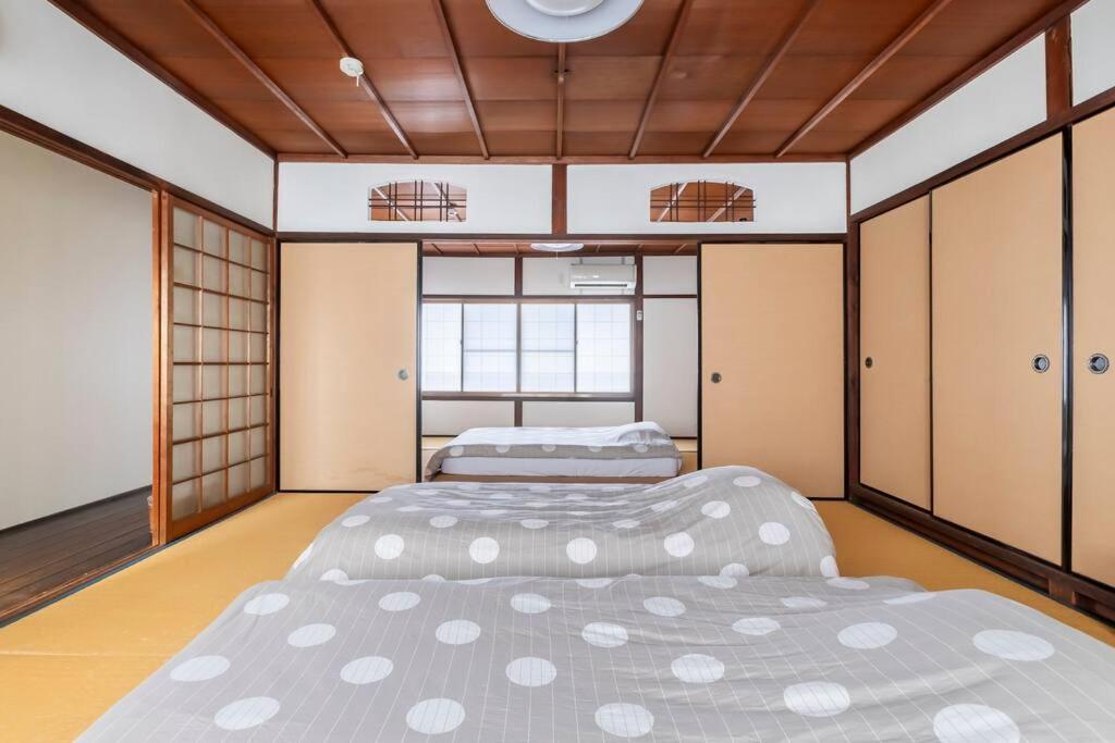 two beds in a room with doors and cabinets at KIX House Wakeikan 和憩館 in Izumi-Sano