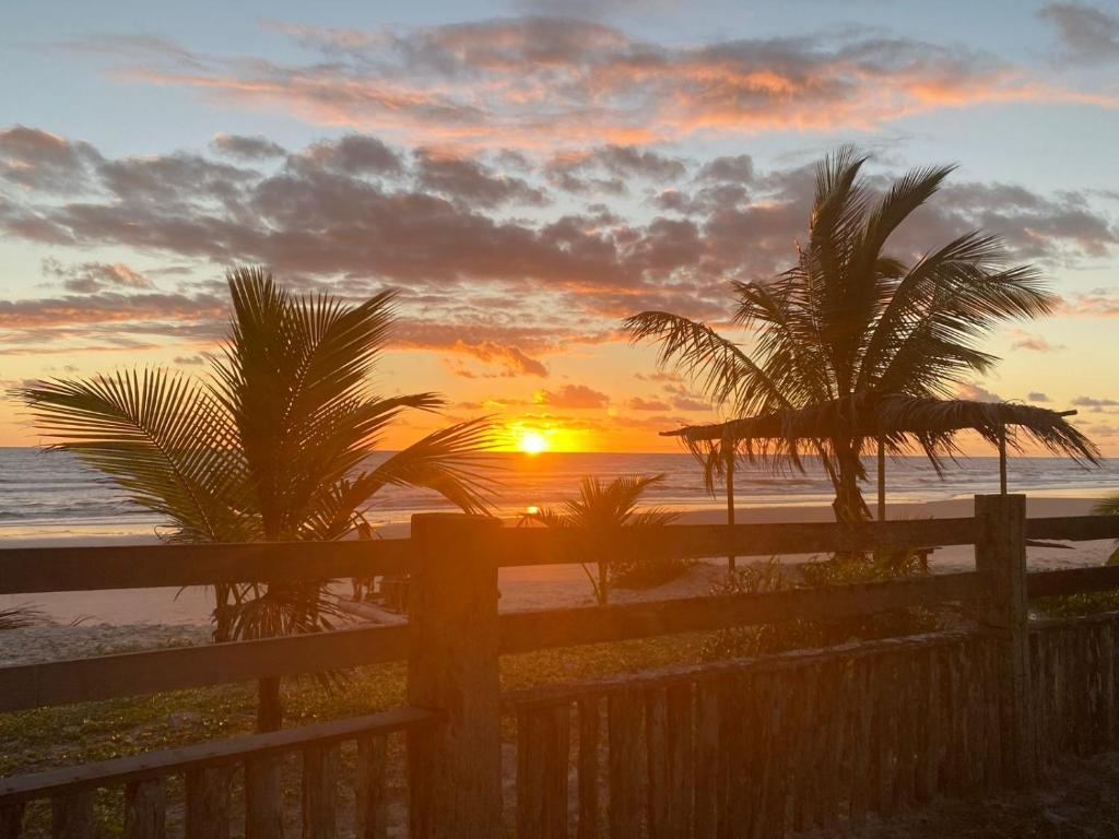 - un coucher de soleil sur la plage avec des palmiers dans l'établissement Chalé Sargi Serra Grande, à Serra Grande