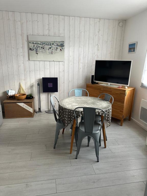 a dining room with a table and chairs and a television at Studio Noirmoutier Plage in La Guérinière