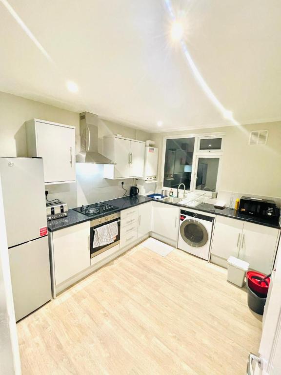 a kitchen with white cabinets and a stove top oven at Ravensbury Home in Mitcham