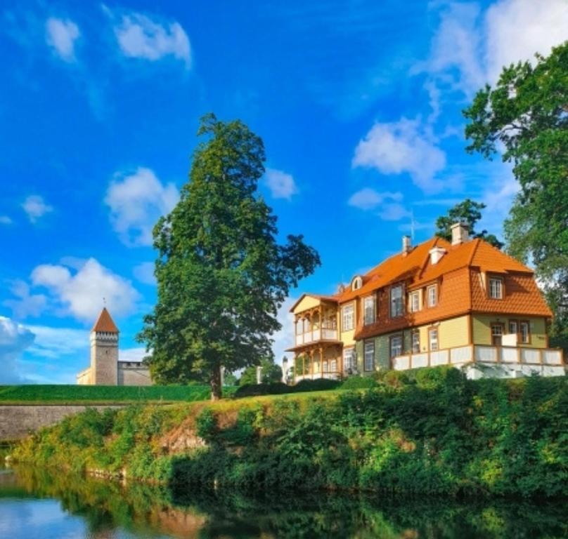 an orange house on a hill next to a river at Ekesparre Boutique Hotel in Kuressaare