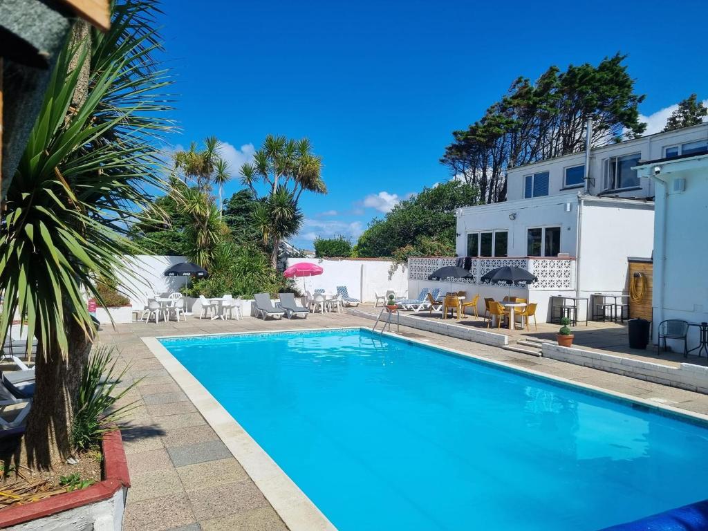 a swimming pool with chairs and umbrellas at a hotel at Pine Lodge in Newquay