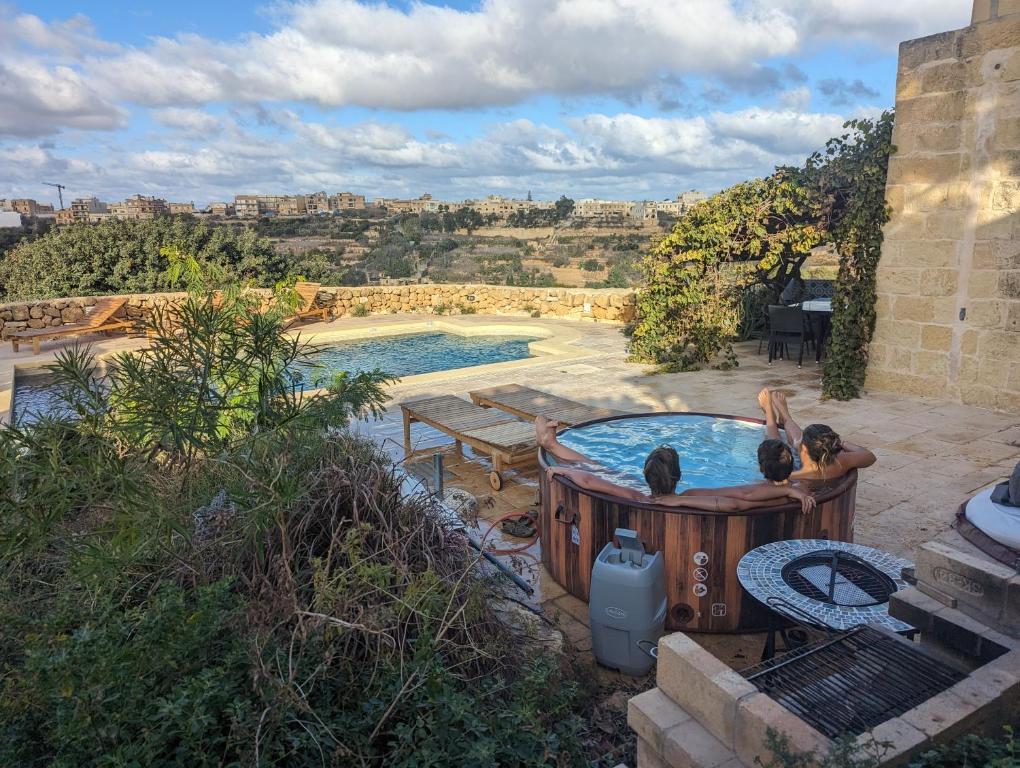 two people are sitting in a hot tub in a yard at Dar Ix-Xemx in Nadur