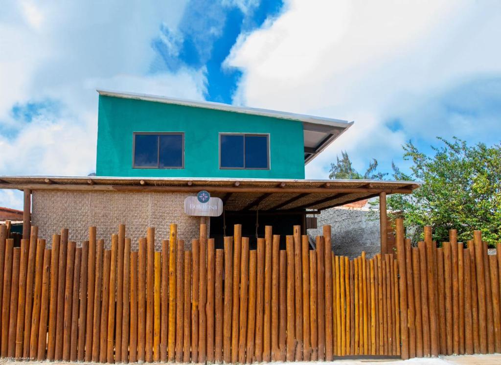 uma casa com um telhado verde atrás de uma cerca de madeira em Bella Rosa Noronha em Fernando de Noronha