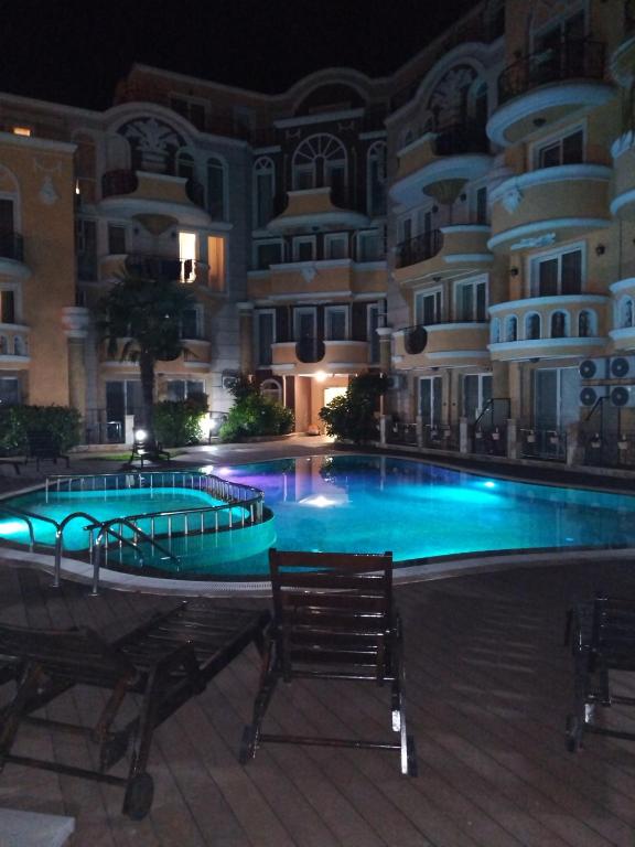 a swimming pool in front of a building at night at MARINA Apartments in Ravda