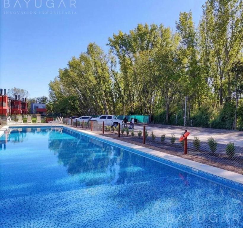 une grande piscine bleue avec des arbres en arrière-plan dans l'établissement Altos de la Cañada, à Mariano Moreno
