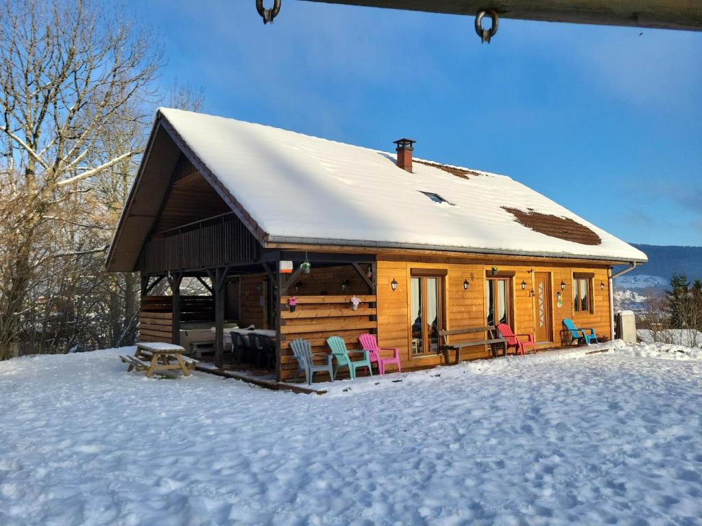 a log cabin with chairs in the snow at le familial avec spa, sauna salle de jeux in Xonrupt-Longemer