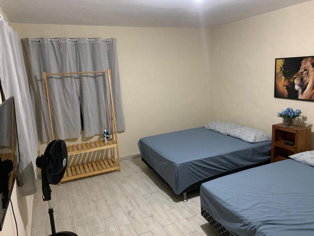 1 Schlafzimmer mit 2 Betten, einem TV und einem Fenster in der Unterkunft Recanto do Peixe Dourado in Casimiro de Abreu